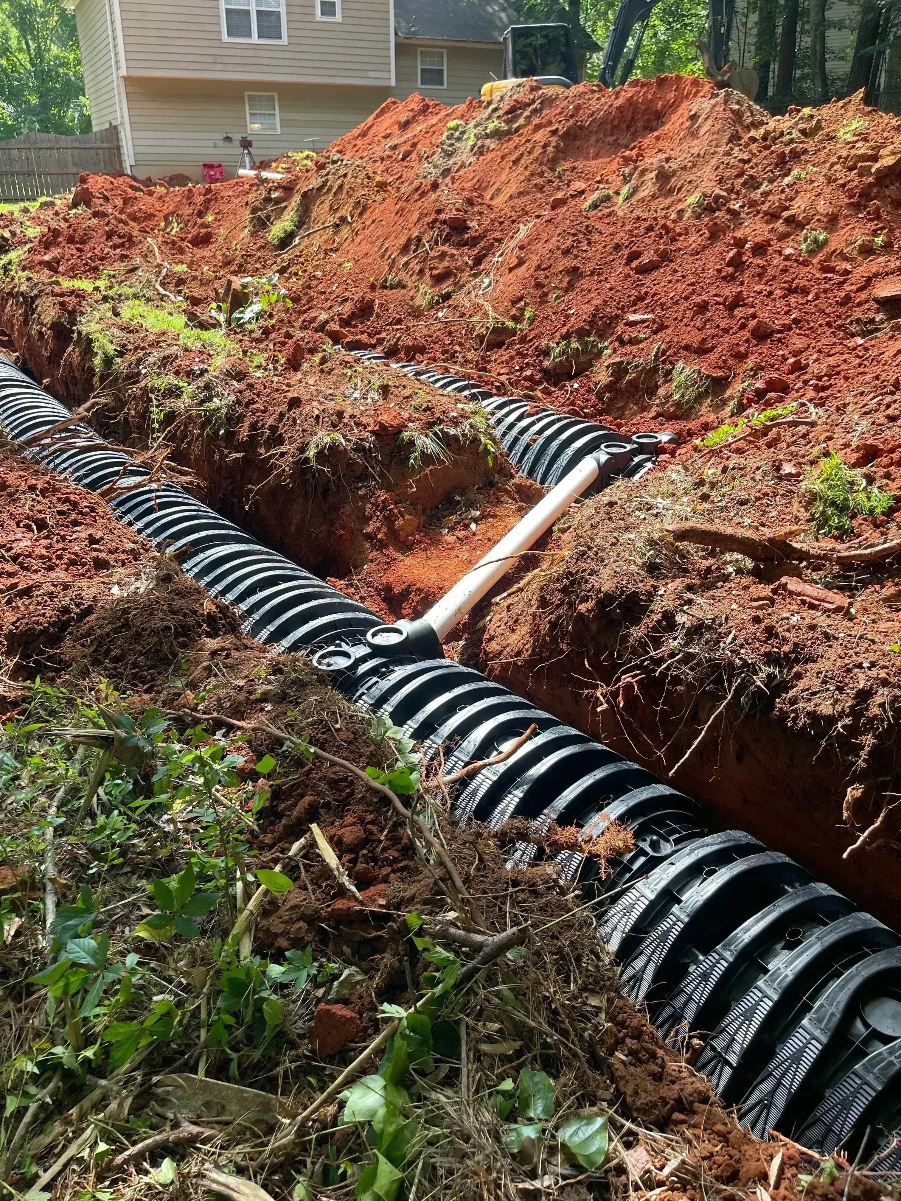 Corrugated plastic septic drain field pipe installed in excavated soil trench