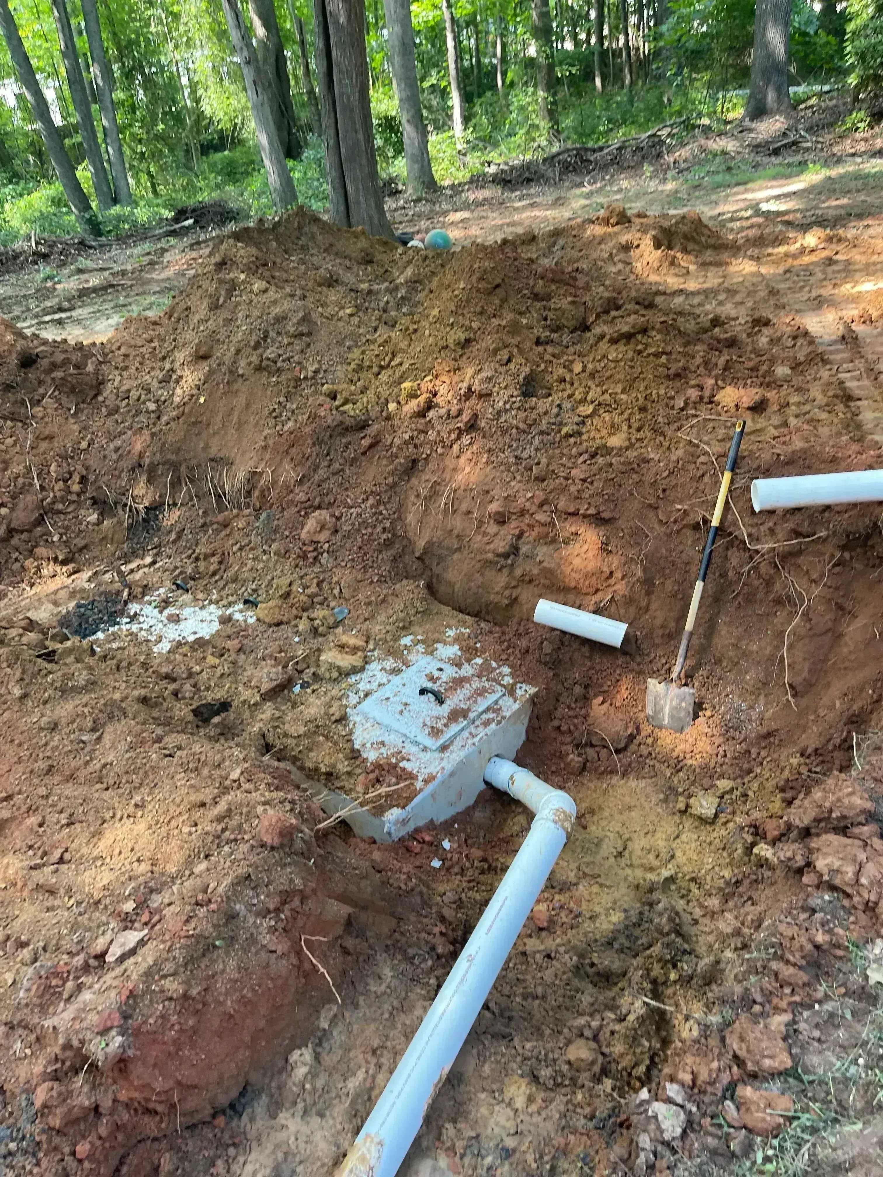 Septic tank installation with PVC piping and distribution lines in excavated trench