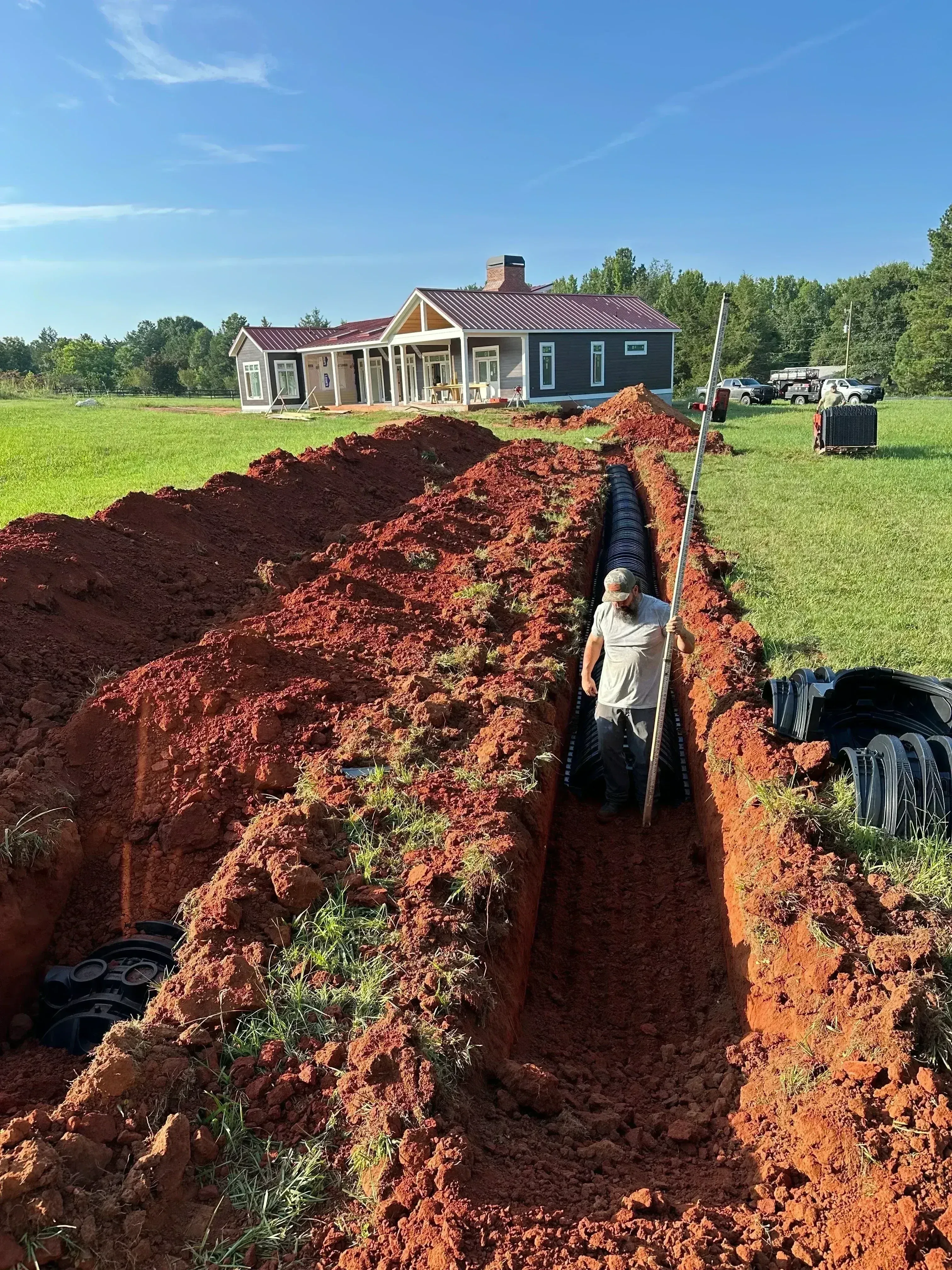 Septic tank excavation with corrugated drainage pipes and clay-lined basin installation