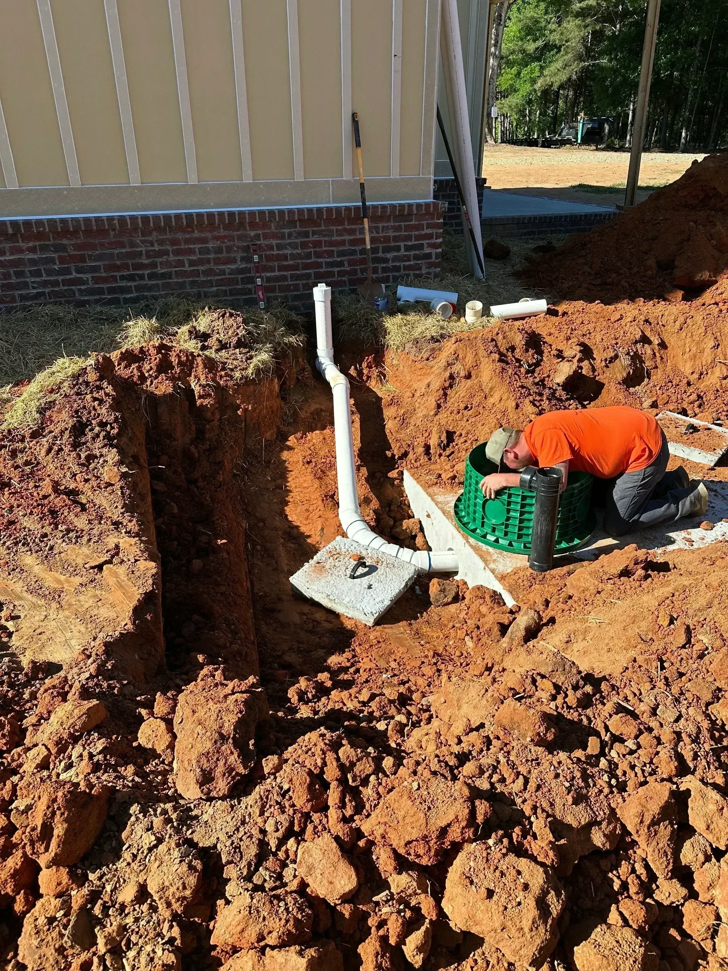 Septic system installation with white PVC pipes and distribution box in excavated soil