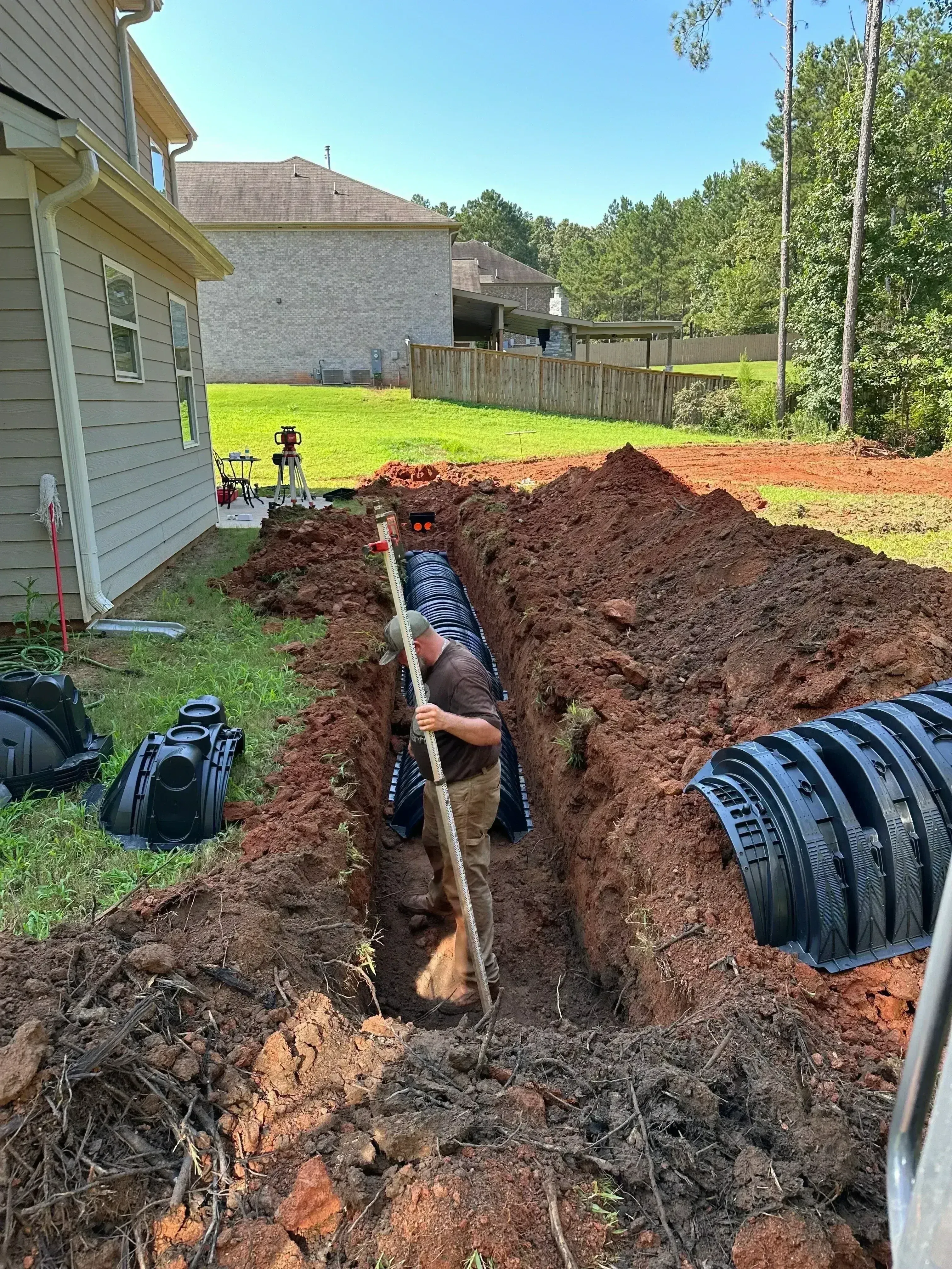 Septic tank installation in excavated pit with plastic tank and drainage components