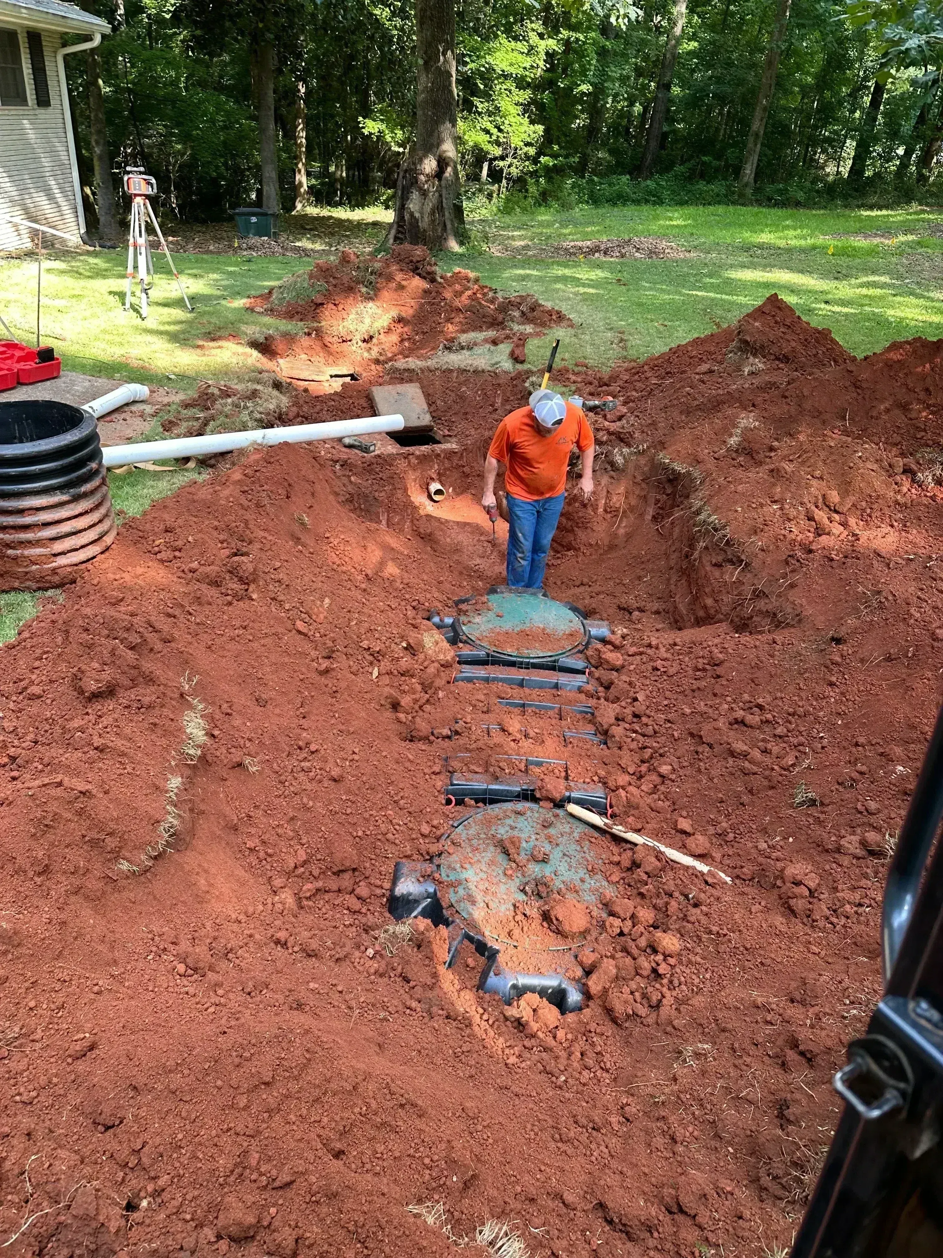 Septic tank and drainage field installation with distribution lines in excavated soil